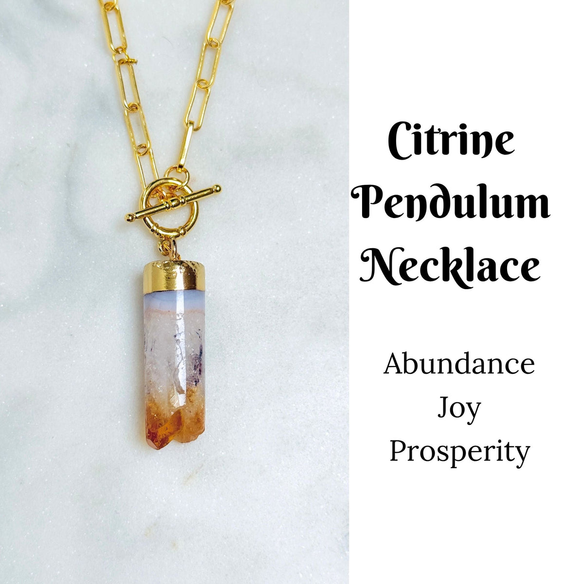 A gold-tone Citrine pendant necklace with a bar clasp and paperclip chain, displayed on a white marble surface next to text that reads 'Citrine Pendulum Necklace' and 'Abundance Joy Prosperity'.