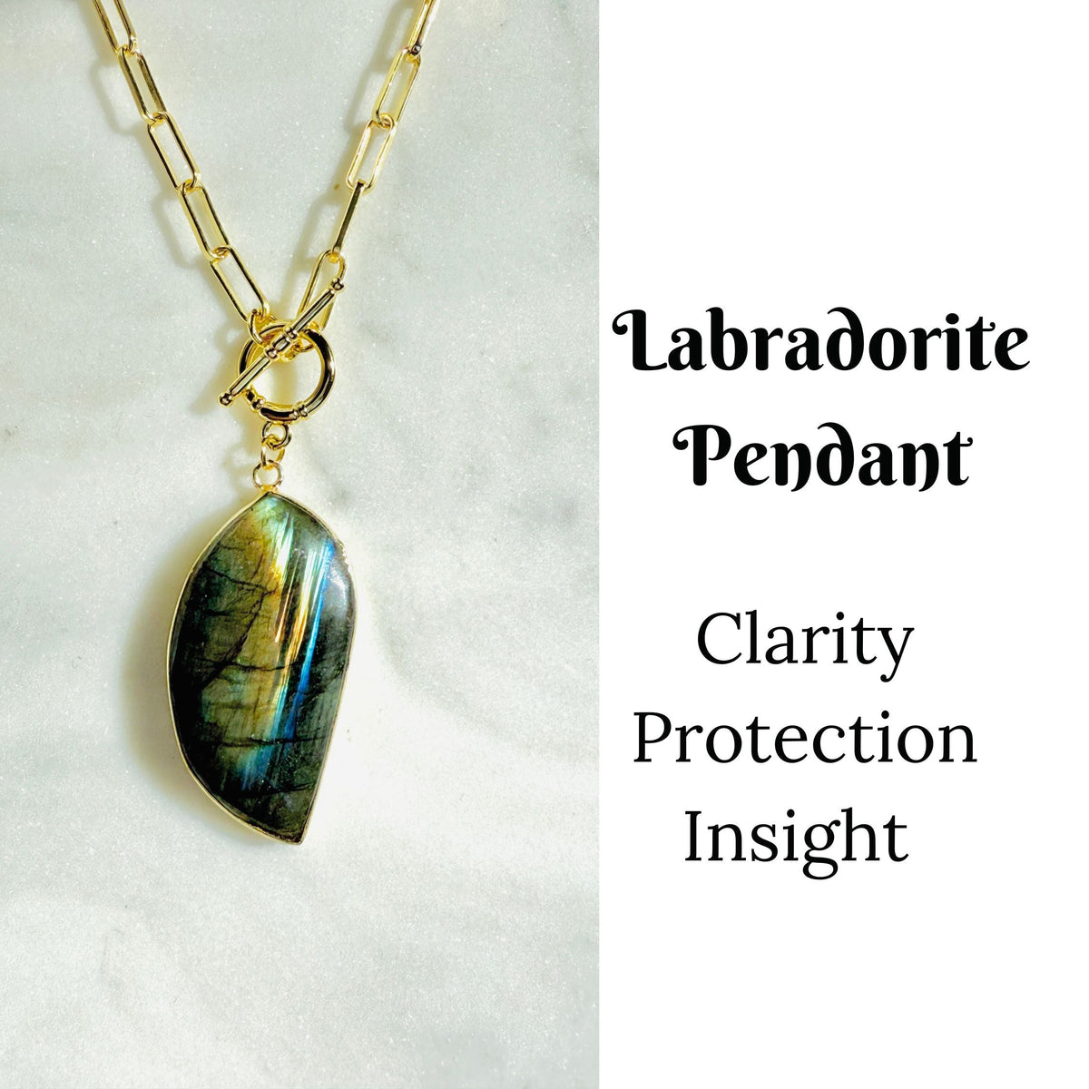 A gold chain necklace with a teardrop-shaped labradorite pendant, displayed on a white marble surface next to text that reads 'Labradorite Pendant Clarity Protection Insight'.